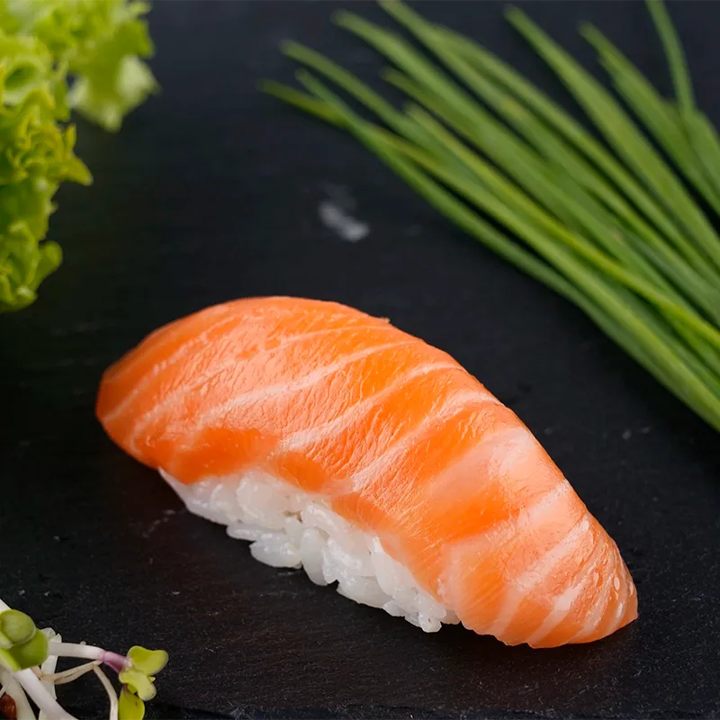 Lachs-Nigiri auf dunklem Schiefer mit Schnittlauch, Food-Nahaufnahme