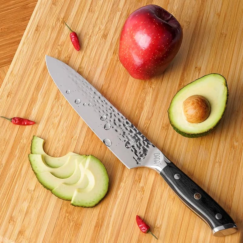Kochmesser mit Apfel, Avocado und Chili auf einem Holzbrett, Food-Aufnahme von oben