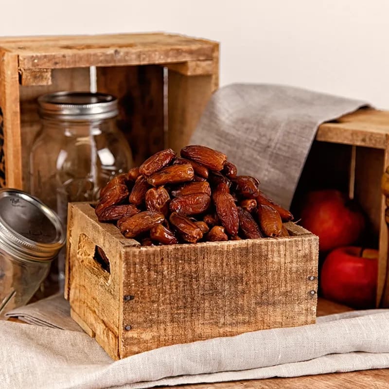 Bio-Datteln in einer Holzkiste mit Äpfeln, Food-Aufnahme im rustikalen Setting