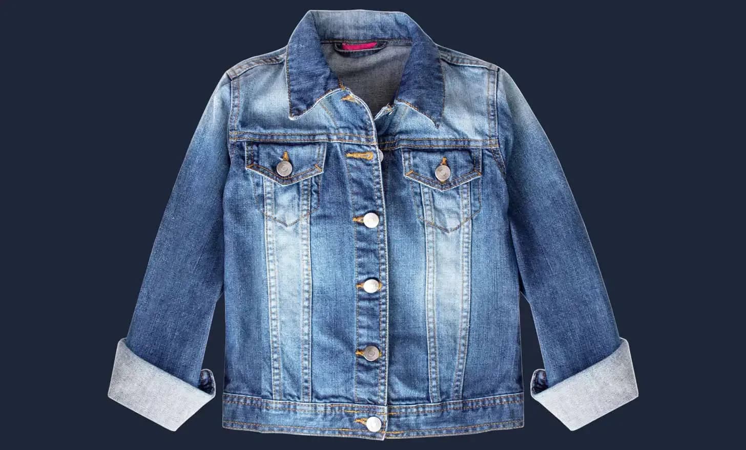 Jeansjacke mit umgeschlagenen Ärmeln, freigestellt vor dunkelblauem Grund