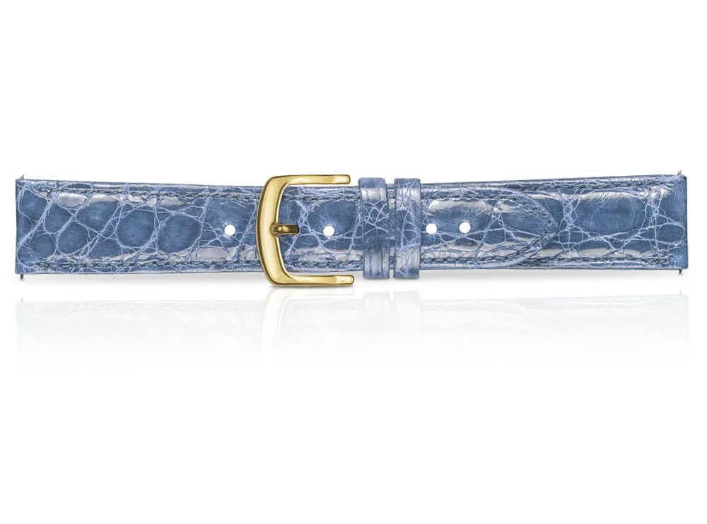 Hellblaues Uhrenarmband in Kroko-Optik mit goldener Schließe, liegend vor Weiß mit leichter Spiegelung