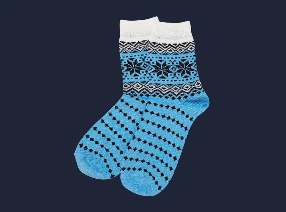 Blaue Wollsocke mit Norwegermuster und Punkten, freigestellt vor dunkelblauem Grund