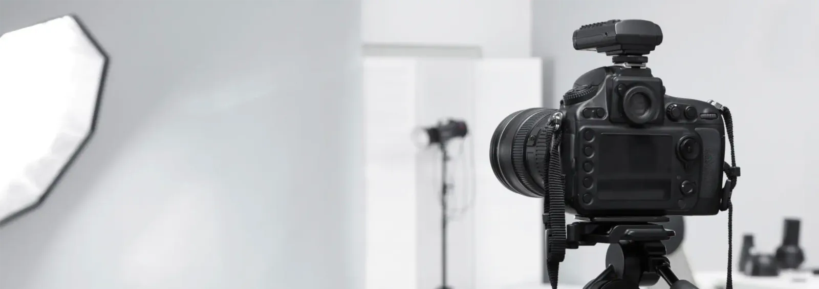 Kamera auf Stativ im Fotostudio mit Softbox und Lichtstativ, Blick über das Set