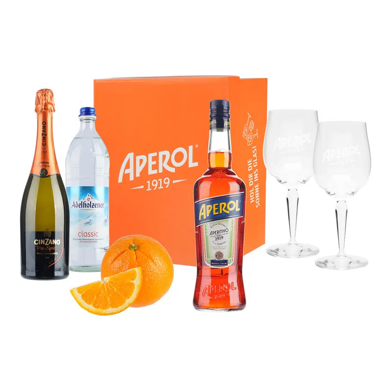 Aperitif-Geschenkset mit Flaschen, zwei Gläsern und Orangen vor oranger Box, Werbefoto vor Weiß