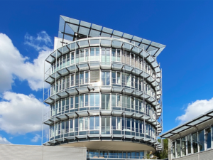 Professionelle Immobilienfotografie des Büroturms der 3W Gruppe von vorne, vor blauem Himmel und vereinzelten Wolken.