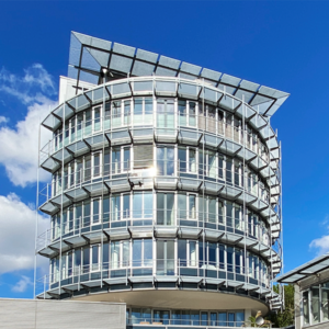Professionelle Immobilienfotografie des Büroturms der 3W Gruppe von vorne, vor blauem Himmel und vereinzelten Wolken.